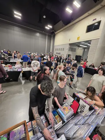 People browsing comic boxes at a card-show table